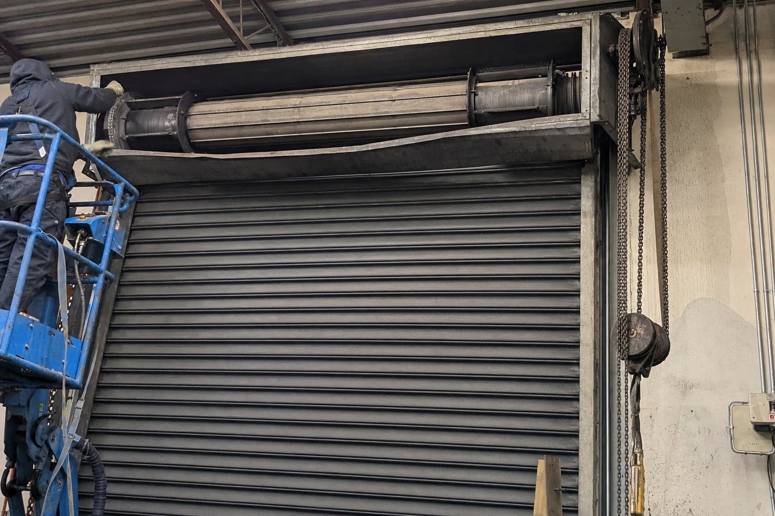 Working on the hood and barrel of a large rolling steel door